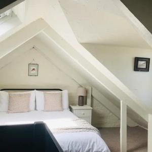 a bedroom with a white bed in a attic at Manderley Cottage, Mousehole in Mousehole
