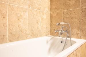 a white bath tub with a faucet in a bathroom at Huckleberry Farm House in Basildon +50 photos