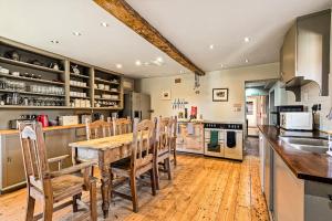 a large kitchen with a wooden table and chairs at Huckleberry Farm House in Basildon