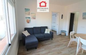 a living room with a blue couch and a table at Apartament Marea Alta in San Juan de Palamós
