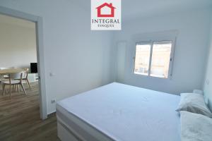 a white bedroom with a bed and a table at Apartament Marea Alta in San Juan de Palamós +7 photos