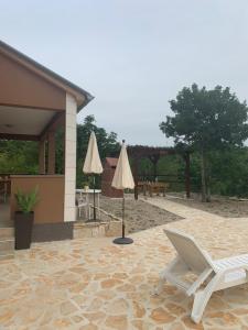 a patio with two white chairs and two umbrellas at Villa Julija with Private Pool in Bilišane