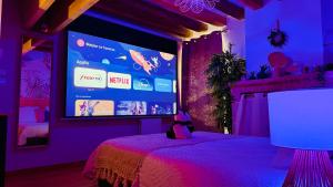 a stuffed animal sitting on a bed in a room with a large screen at Le Coconut 5 min du Zoo Beauval in Saint-Aignan