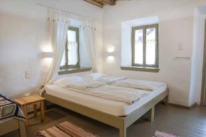 a bed in a room with two windows at Ghermaniko Guesthouse in Damouchari
