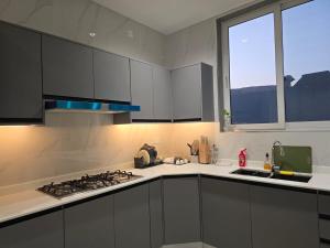 a kitchen with white cabinets and a stove and a window at Sea Wind Chalet in Qalhāt