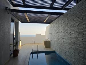 a room with a swimming pool and a brick wall at Sea Wind Chalet in Qalhāt