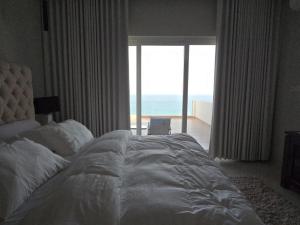 a bedroom with a large bed with a view of the ocean at Sea Wind Chalet in Qalhāt +8 photos