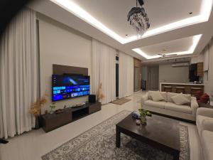 a living room with a couch and a flat screen tv at Sea Wind Chalet in Qalhāt