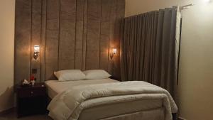 a bedroom with a large bed with a wooden headboard at Royalz Hotel in Lahore +31 photos