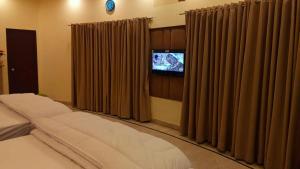 a bedroom with a bed and a tv and curtains at Royalz Hotel in Lahore