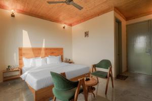 a bedroom with a white bed and a green chair at Hotel Sarai Bharatgarh in Nohan