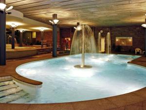 a swimming pool with a fountain in a building at Mercure Andorra in Andorra la Vella