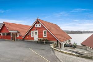 a red building with a picnic table in front of a lake at Cabin by the lake in Sveio