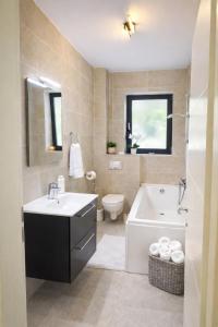 a bathroom with a sink and a tub and a toilet at A B V Central Apartment- Unitate autorizata de Ministerul Turismului in Râmnicu Vâlcea +16 photos