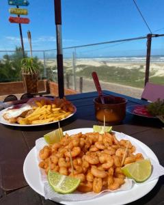 a table topped with plates of food with tater tots and french fries at Beira Mar in Tramandaí