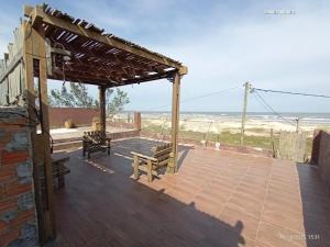 a deck with benches and a pergola and the beach at Beira Mar in Tramandaí