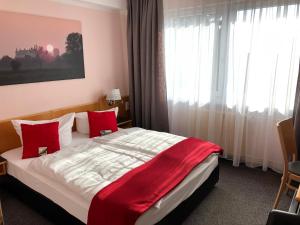 a bedroom with a large bed with red pillows at Hotel am Tierpark in Güstrow