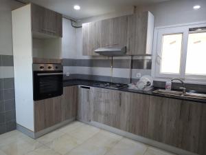a kitchen with wooden cabinets and a sink and a window at Appartements Mimosa in Tefeschoun