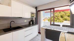 a kitchen with white cabinets and a sink and a window at Apartments Padovan in Rab