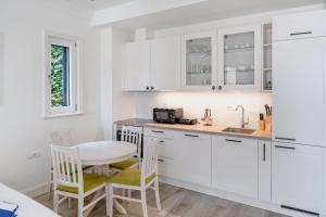 a kitchen with white cabinets and a table and chairs at Lustica-Marina GOLD APARTMAN in Radovici