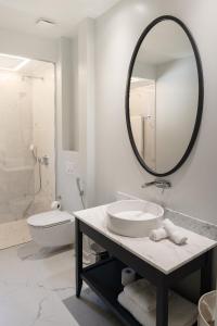a white bathroom with a sink and a mirror at Lustica-Marina GOLD APARTMAN in Radovici