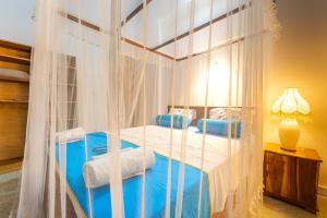 a bedroom with a canopy bed with blue pillows at The One Hikkaduwa in Hikkaduwa +21 photos