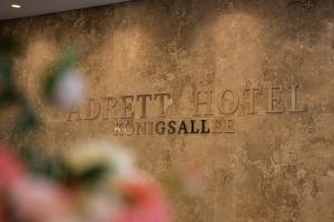 a sign on a wall with flowers in front of it at Adrett Hotel Königsallee in Düsseldorf