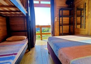 two beds in a wooden room with a window at Hospedaria Chalés Rota Do Sol PDR - Aluguel de chalés confortáveis na Praia do Rosa SC in Praia do Rosa