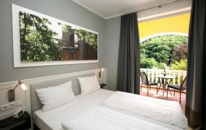 a bedroom with a bed and a balcony with a table at Jugendstilhotel Trifels in Annweiler am Trifels