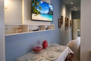 a dining room with a table and a tv on the wall at Costa Family-Little house in the center in Santa Rita do Sapucaí