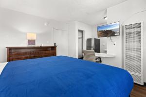 a large blue bed in a room with a desk at Studio Lodge Hotel in Hewitt