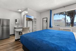 a bedroom with a bed and a desk and a refrigerator at Studio Lodge Hotel in Hewitt