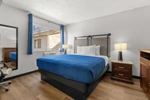 a bedroom with a bed with blue sheets and a window at Studio Lodge Hotel in Hewitt +12 photos