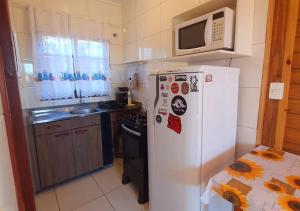 a kitchen with a white refrigerator and a microwave at Hospedaria Chalés Rota Do Sol PDR - Aluguel de chalés confortáveis na Praia do Rosa SC in Praia do Rosa
