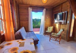 a living room with a tv and a couch and a table at Hospedaria Chalés Rota Do Sol PDR - Aluguel de chalés confortáveis na Praia do Rosa SC in Praia do Rosa