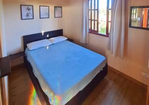 a bedroom with a large bed with a blue blanket at Hospedaria Chalés Rota Do Sol PDR - Aluguel de chalés confortáveis na Praia do Rosa SC in Praia do Rosa