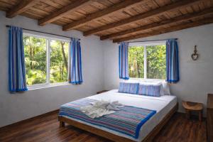 a bedroom with a bed and two windows at Kin Resort Lodge in Maya Beach