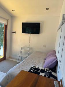 a bedroom with a bed and a tv on the wall at Cabaña Sobre Playa Lago Gutiérrez 2 in San Carlos de Bariloche