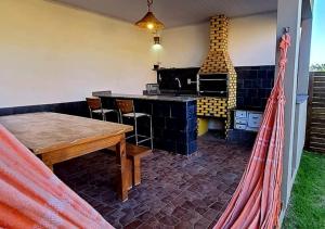 a hammock in a room with a table and a fireplace at Hospedaria Chalés Rota Do Sol PDR - Aluguel de chalés confortáveis na Praia do Rosa SC in Praia do Rosa +21 photos