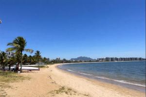 a sandy beach with palm trees and the ocean at Flat Praia Century Camburi in Vitória