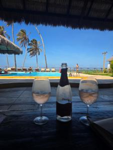 two wine glasses sitting on a table next to the ocean at Eco Paradise 129 in Caucaia