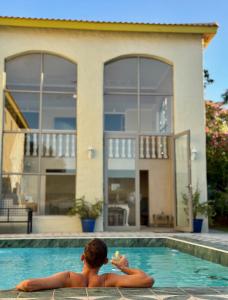 a man sitting in a swimming pool in front of a house at Grande Casa - Central Stellenbosch in Stellenbosch