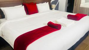 a bed with red and white blankets and pillows on it at Gem Villa Inn in Lesoma +18 photos