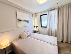 a white bedroom with a large bed and a window at Apartamenty Polna Park in Duszniki Zdrój