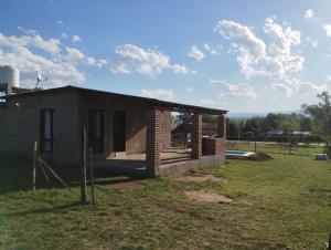 a small brick house in a field with clouds in the sky at Cabaña gio in Potrero de Garay