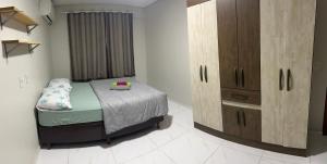 a bedroom with a bed and a wooden cabinet at Apartamento em Pomerode - 203 in Pomerode
