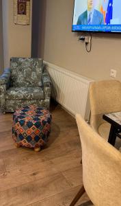 a living room with a tv and chairs and a ottoman at Nino's Home in Bakuriani