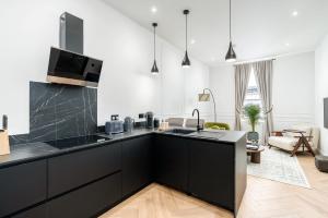 a kitchen with black cabinets and a living room at Luxury High-Ceiling Apartment Central Altrincham in Altrincham +28 photos