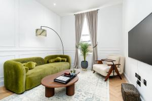 a living room with a green couch and a table at Luxury High-Ceiling Apartment Central Altrincham in Altrincham