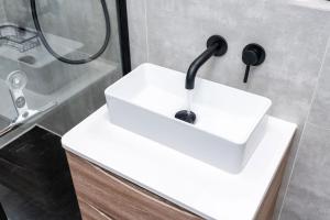 a white sink in a bathroom with a shower at Luxury High-Ceiling Apartment Central Altrincham in Altrincham